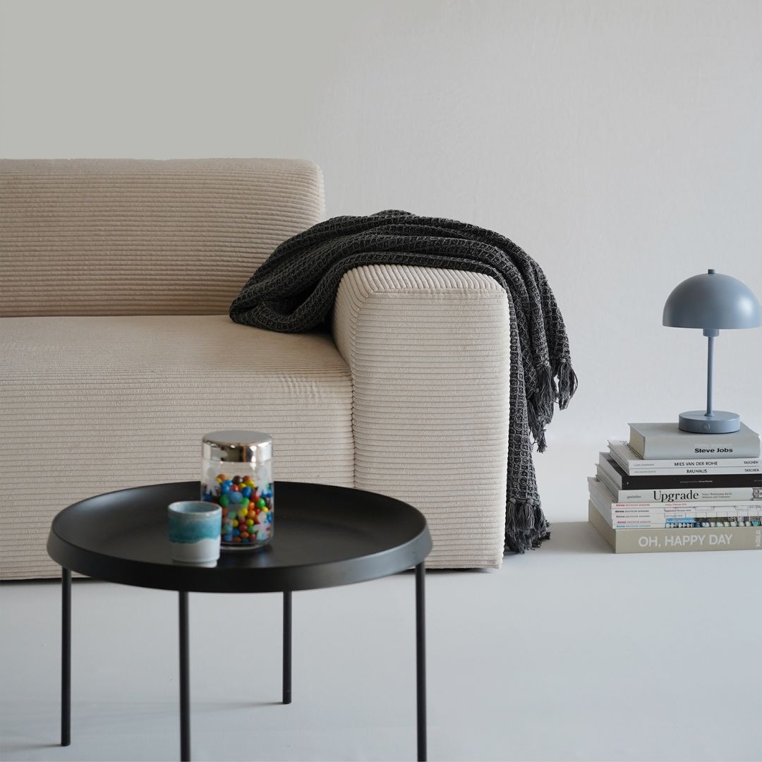 Canapé en velours côtelé beige en vue partielle, accoudoir du canapé