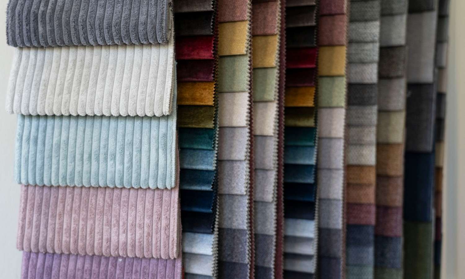 Échantillons de tissu dans différentes couleurs et matières, suspendus côte à côte et les uns sous les autres.